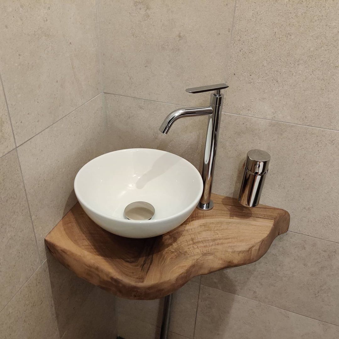 Organisch gevormd wastafelblad van massief hout in de hoek van een badkamer
